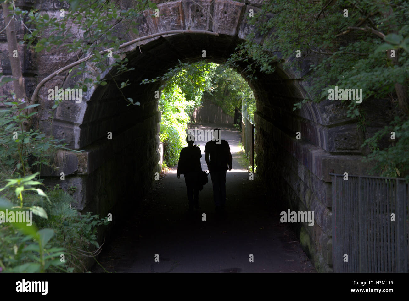 Silhouetten von Menschen in der Stadt vor dem Hintergrund des Eingangs im Brücke-Tunnel im Westend von Glasgow im park Stockfoto