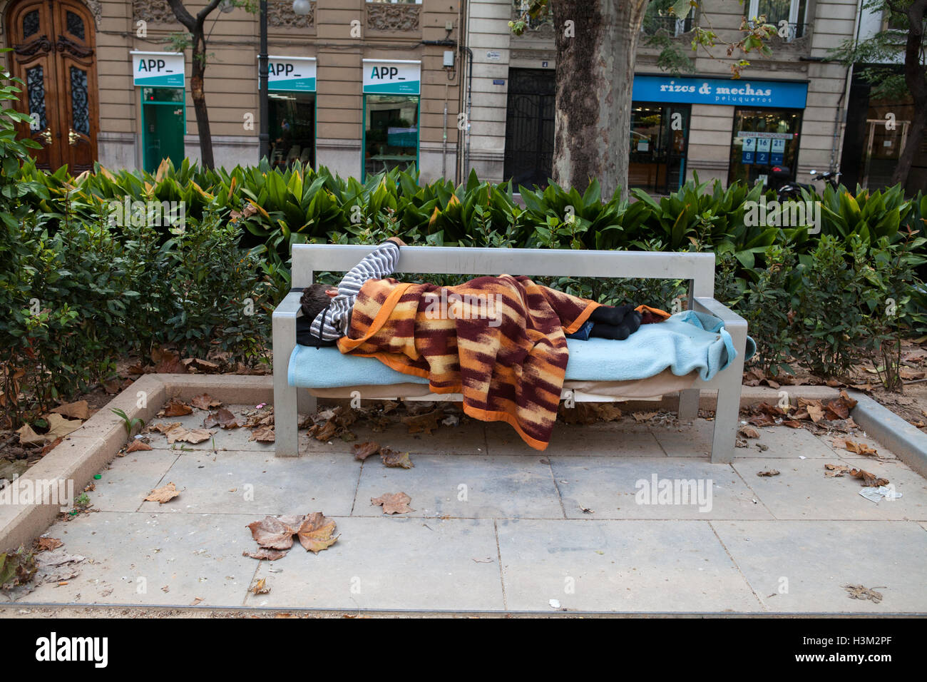 Obdachloser schlafen auf einer Bank in Valencia Stockfoto
