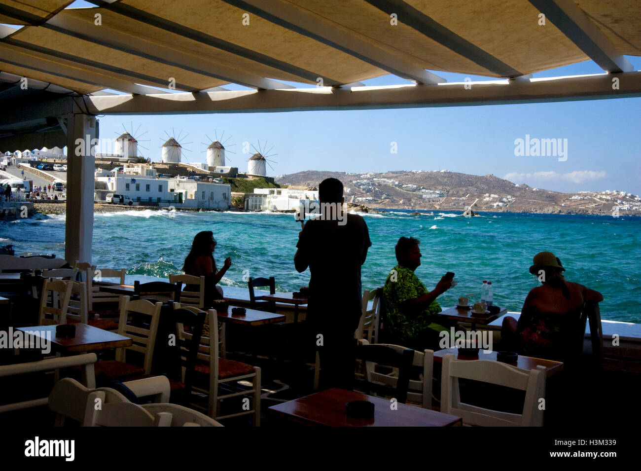 Ansicht von Windmühlen von Seaside Café in Mykonos, Griechenland Stockfoto