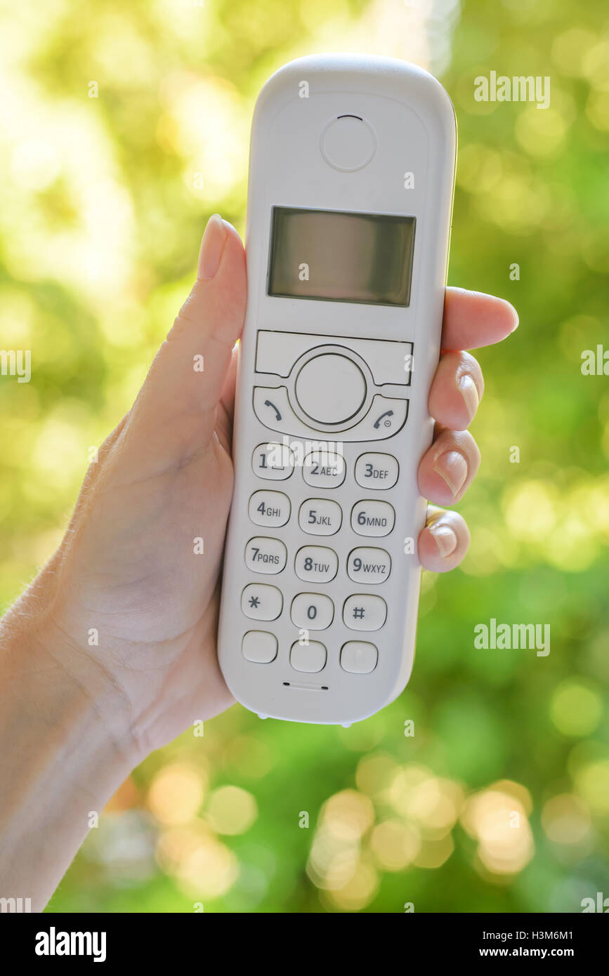 Weibliche Hand schnurlose Festnetz Telefonhörer im Freien, mit selektiven Fokus Stockfoto