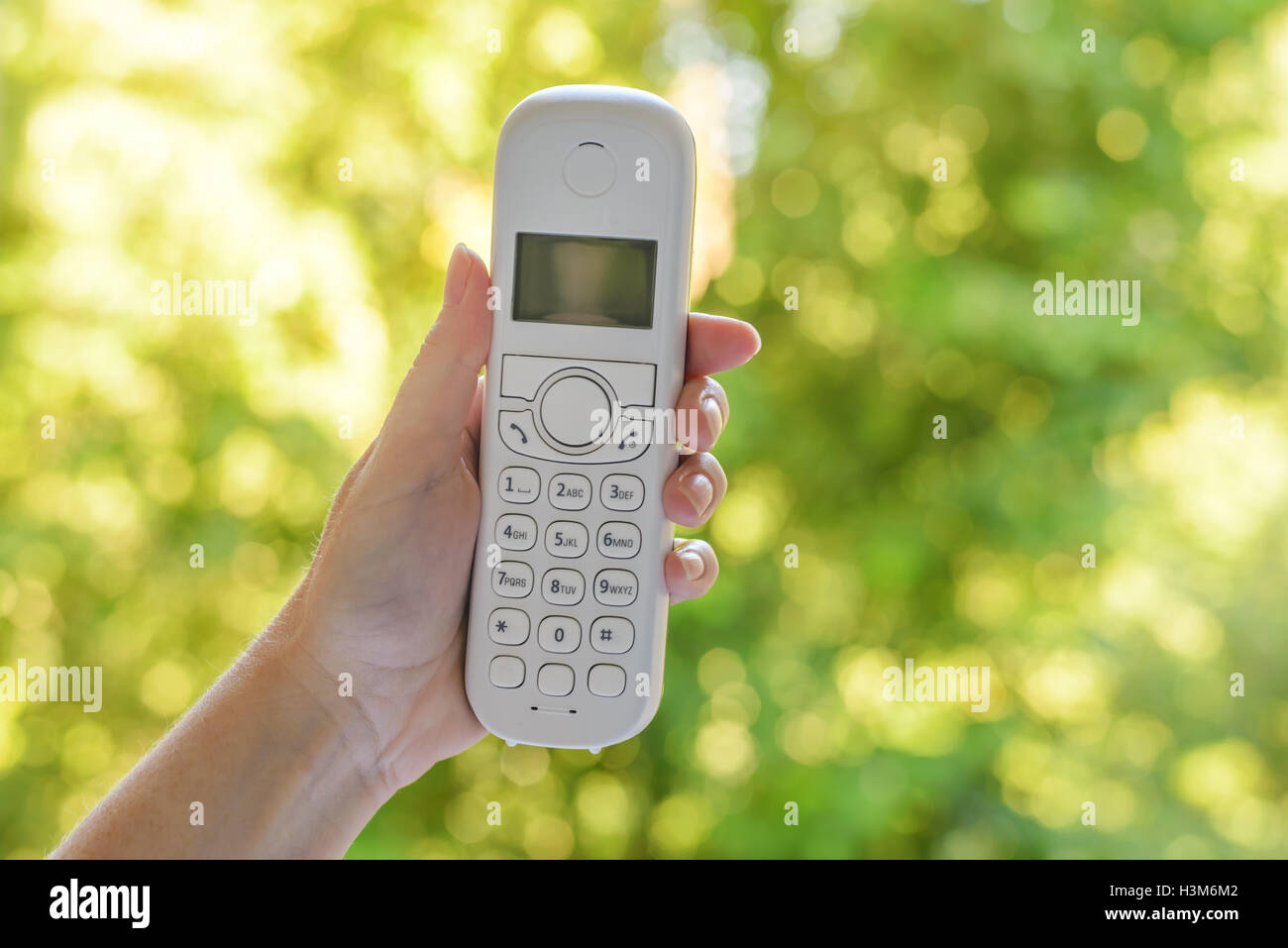 Weibliche Hand schnurlose Festnetz Telefonhörer im Freien, mit selektiven Fokus Stockfoto