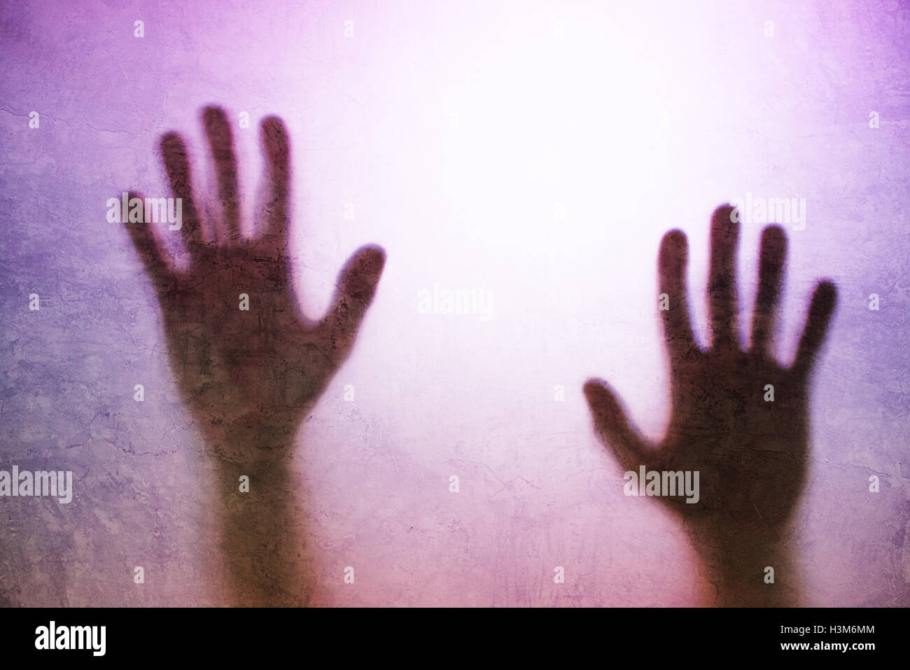 Eingeschlossene Person Konzept mit Rückseite beleuchteten Silhouette der Hände hinter Mattglas, nützlich als anschauliches Bild für den Menschenhandel, Stockfoto