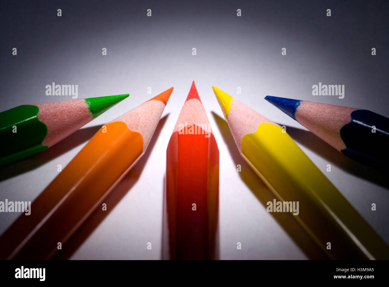 Fünf Bleistifte (dunkelblau, grün, rot, gelb, Orange) auf einem dunklen Hintergrund.  Verfügbar in hoher Auflösung und verschiedenen Größen. Stockfoto