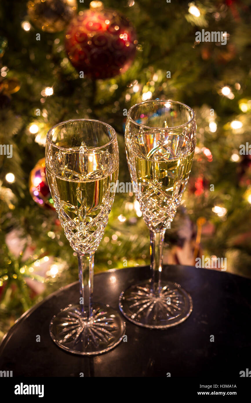 Ein Satz von zwei Sektgläser gefüllt mit Champagner ruht auf einem Tisch vor einem Weihnachtsbaum. Stockfoto