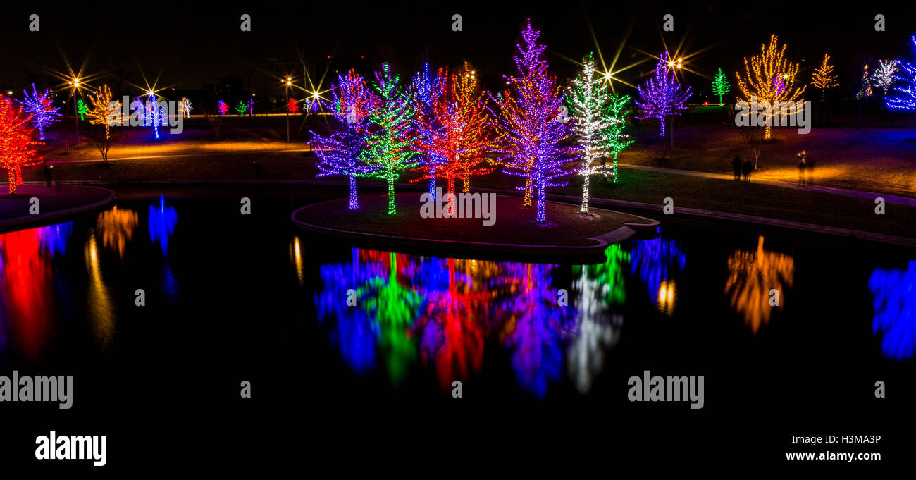 Einen Panoramablick über Bäume, die sind bedeckt mit bunten Weihnachtsbeleuchtung und auf der Oberfläche dieser Teich reflektiert. Stockfoto
