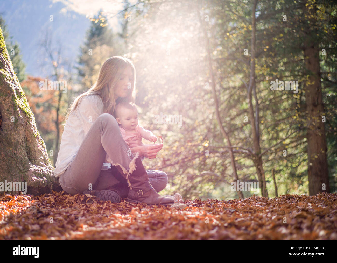 Mutter und Tochter auf Herbst Blatt sitzen bedeckt Waldboden Stockfoto
