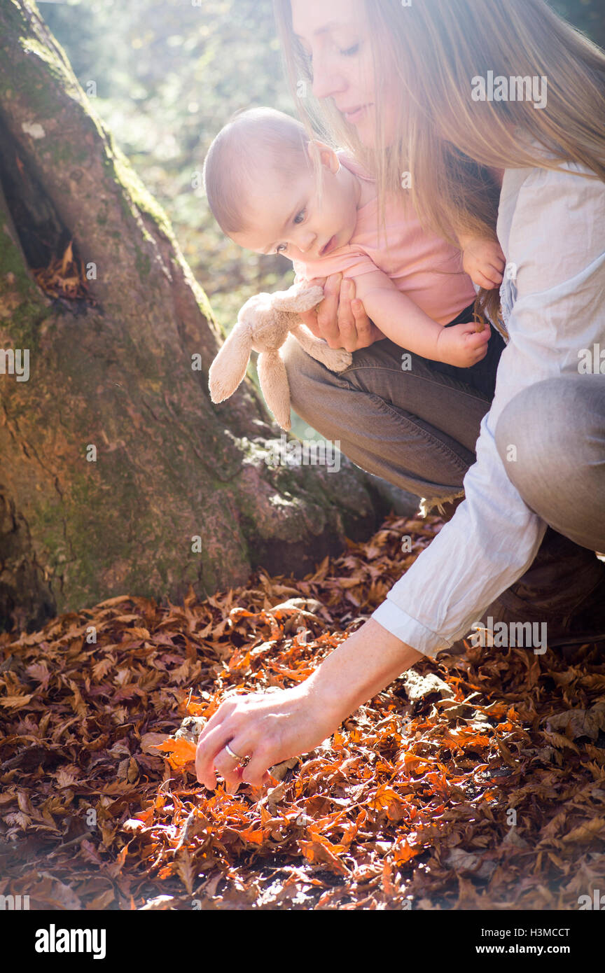 Mutter und Tochter hockend untersuchen lässt auf Waldboden Stockfoto