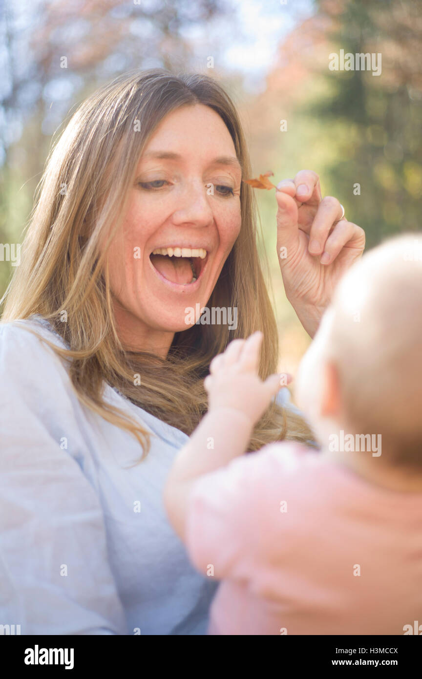 Mutter und Tochter spielen mit Blatt lächelnd Stockfoto