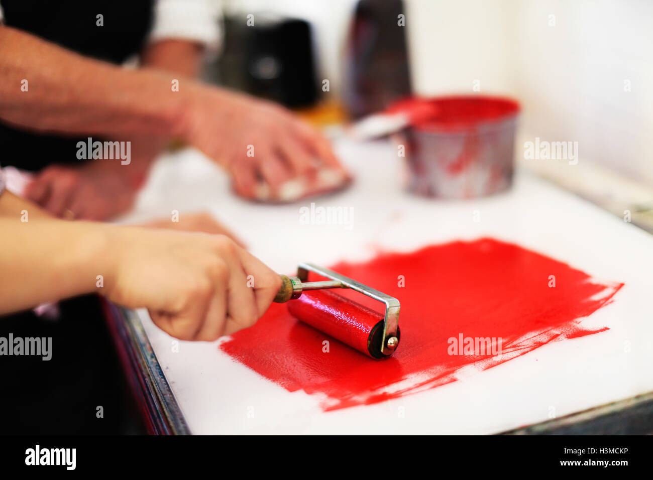 Nahaufnahme der Hände mit Tintenrolle für Buchdruck in Buch-Kunst-Werkstatt Stockfoto