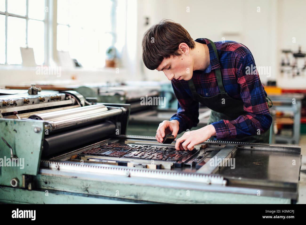 Junger Mann arbeiten an Letterpress Maschine in Buch-Kunst-Werkstatt Stockfoto