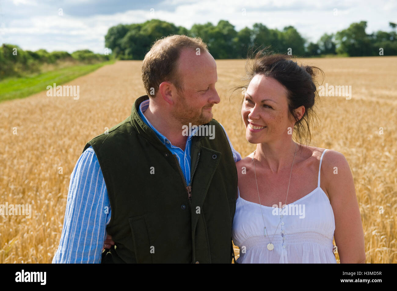 Mitte erwachsenes paar Spaziergang durch Feld Lächeln Stockfoto