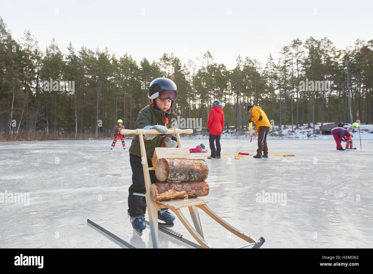 Jungen lernen Schlittschuh mit Tretschlitten auf zugefrorenen See, Hotels, Schweden Stockfoto