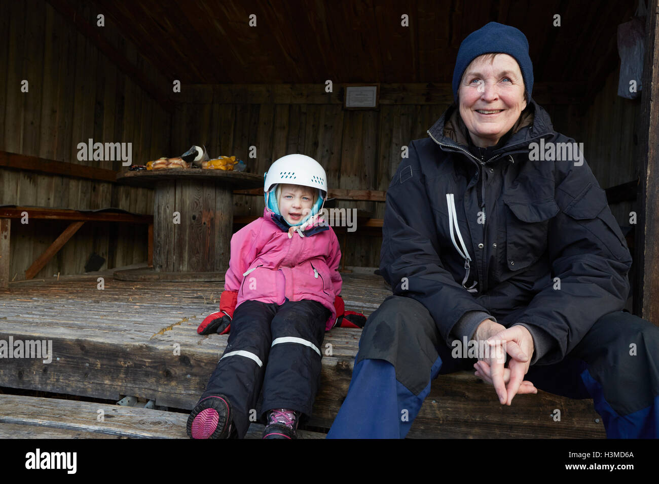 Mädchen mit Ski Helm sitzt auf Scheune Schritt mit Großmutter, Hotels, Schweden Stockfoto