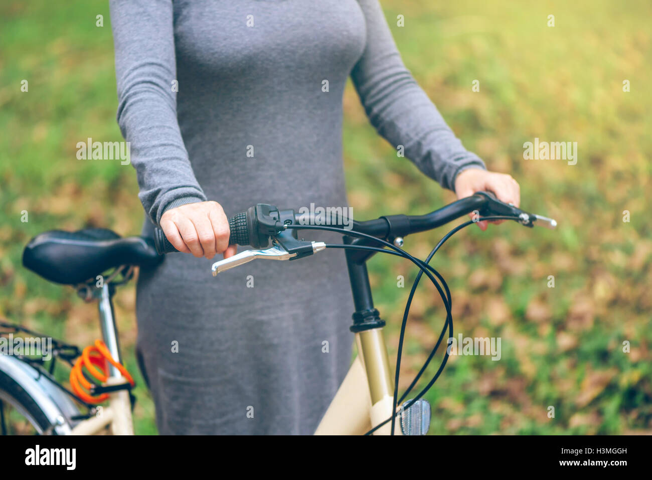 Frau posiert mit ihrem Fahrrad im Park im Herbst. Nicht erkennbare attraktive junge Erwachsenfrau mit Vintage retro-bike Stockfoto
