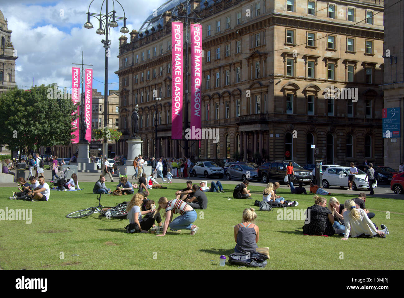 George Square und die Stadt Kammern mit der Kenotaph in Glasgow Stadtzentrum einheimische und Touristen entspannen und die Sonne genießen Stockfoto