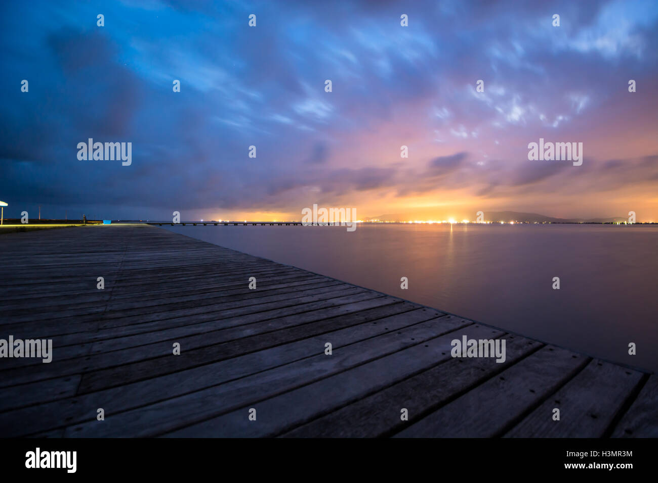 Ferne Lichter beobachtet von einem hölzernen Pier. Stockfoto