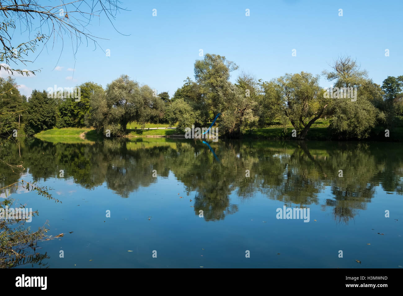 Bäume, reflektiert in einem ruhigen Fluss an einem sonnigen Herbsttag Stockfoto