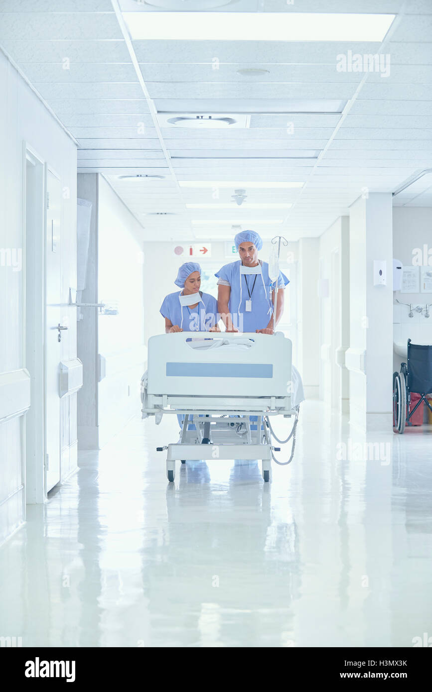 Männlichen und weiblichen Krankenschwestern Patientenbett auf Krankenhausflur schieben Stockfoto