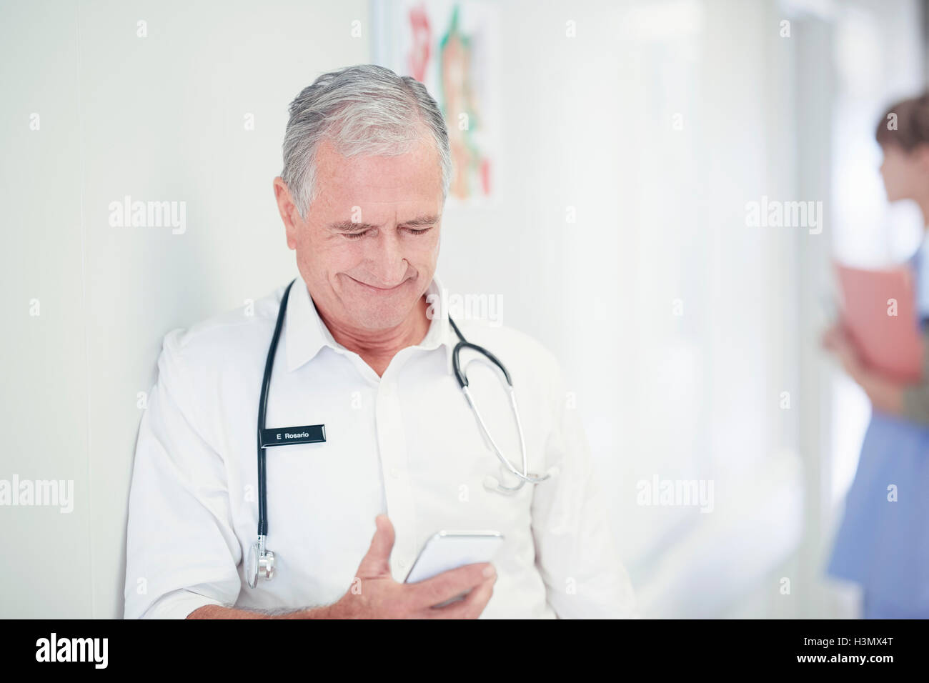 Männliche Oberärztin lesen Smartphone Nachricht im Krankenhaus Stockfoto