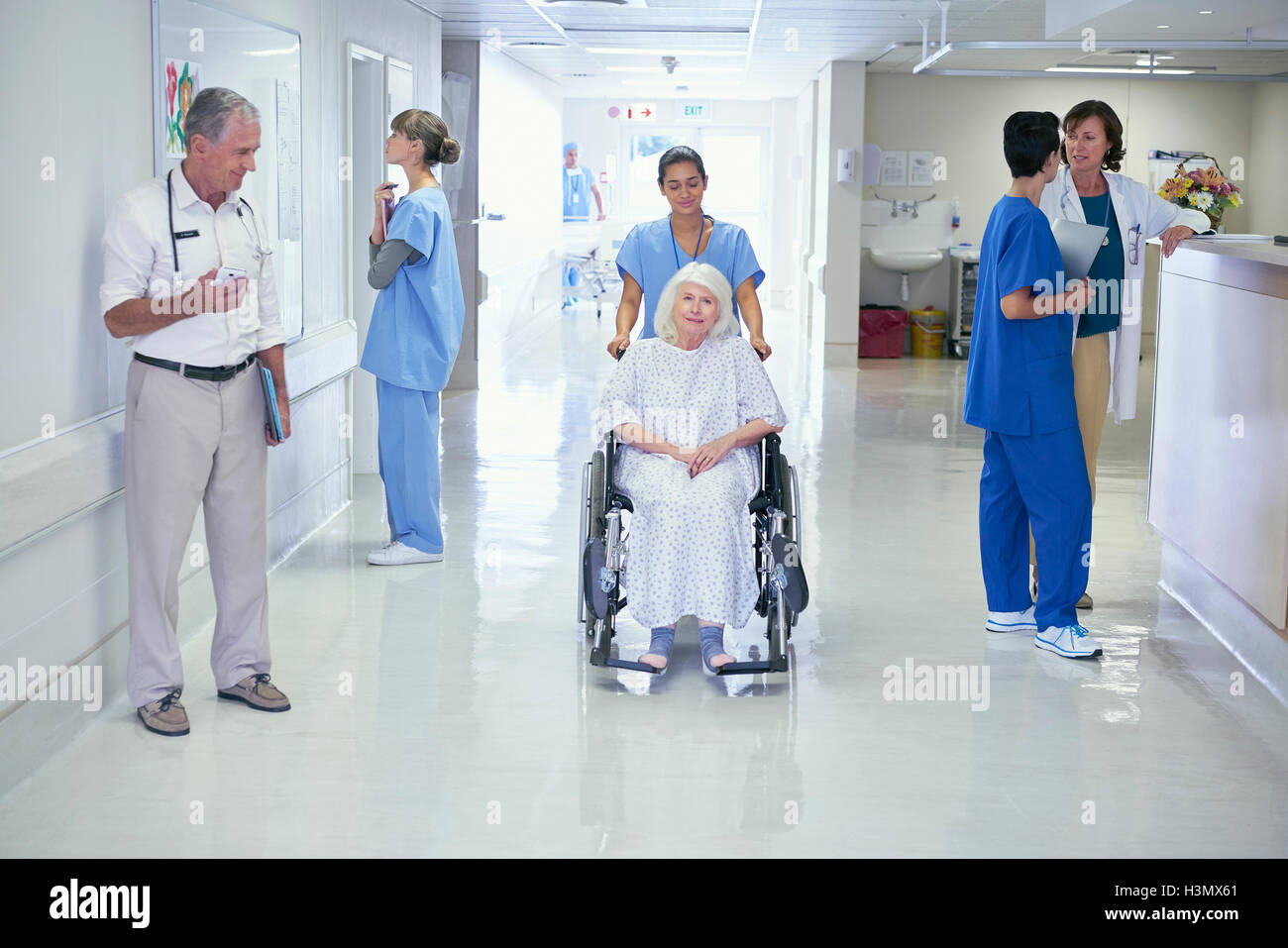 Krankenschwester drängen ältere Patientin im Rollstuhl auf Krankenstation Stockfoto