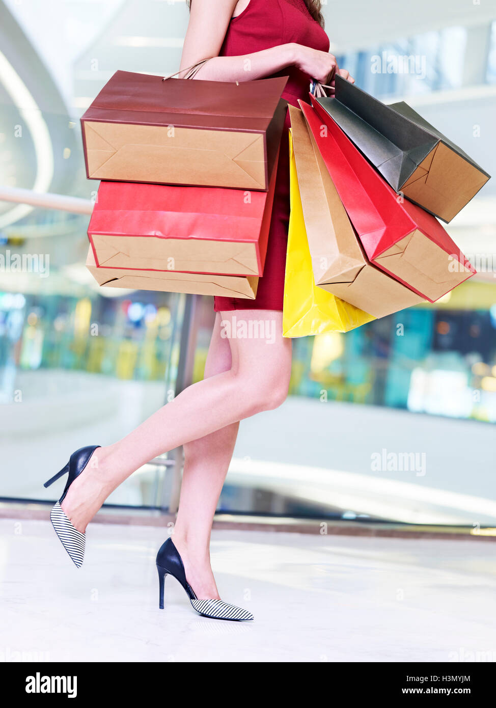 junge trendige und modische Frau weibliche Shopper farbiges Papier Tragetaschen in modernen Shopping-Mall zu Fuß Stockfoto
