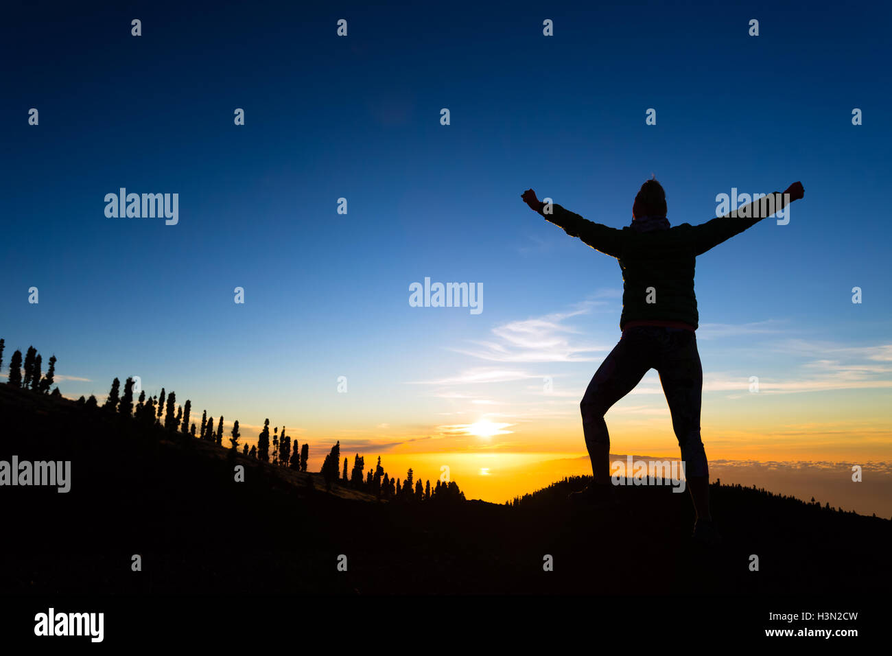 Frau Wanderer mit ausgestreckten in Bergen. Weibliche Schönheit Läufer, Hände hoch und genießen Sie inspirierende Sonnenuntergang Landschaft auf Felsen Stockfoto