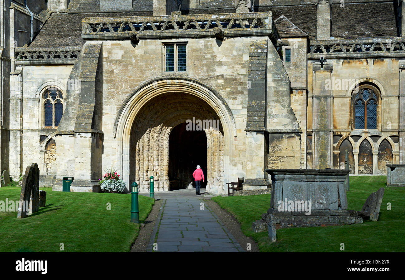 Frau zu Fuß in das Eingangsportal von Malmesbury Abbey, Malmesbury, Wiltshire, England UK Stockfoto