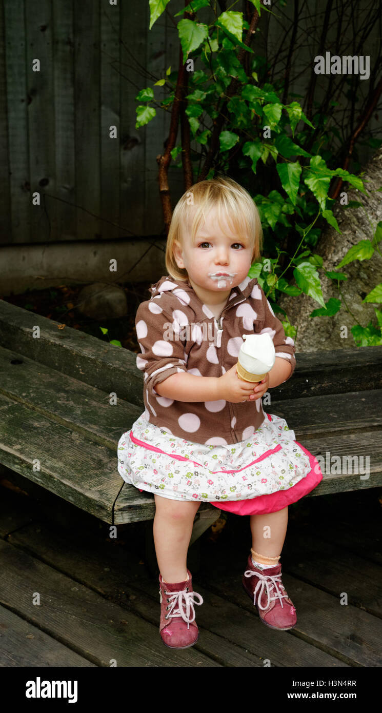 Ein kleines Mädchen (2 Jahre alt) Essen ein Eis Stockfoto