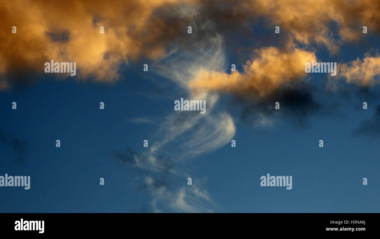 Zwirbelte Spinnerei Contrail Cloud im Hintergrund mit goldenen Sonnenuntergang farbige Wolken im Vordergrund Stockfoto