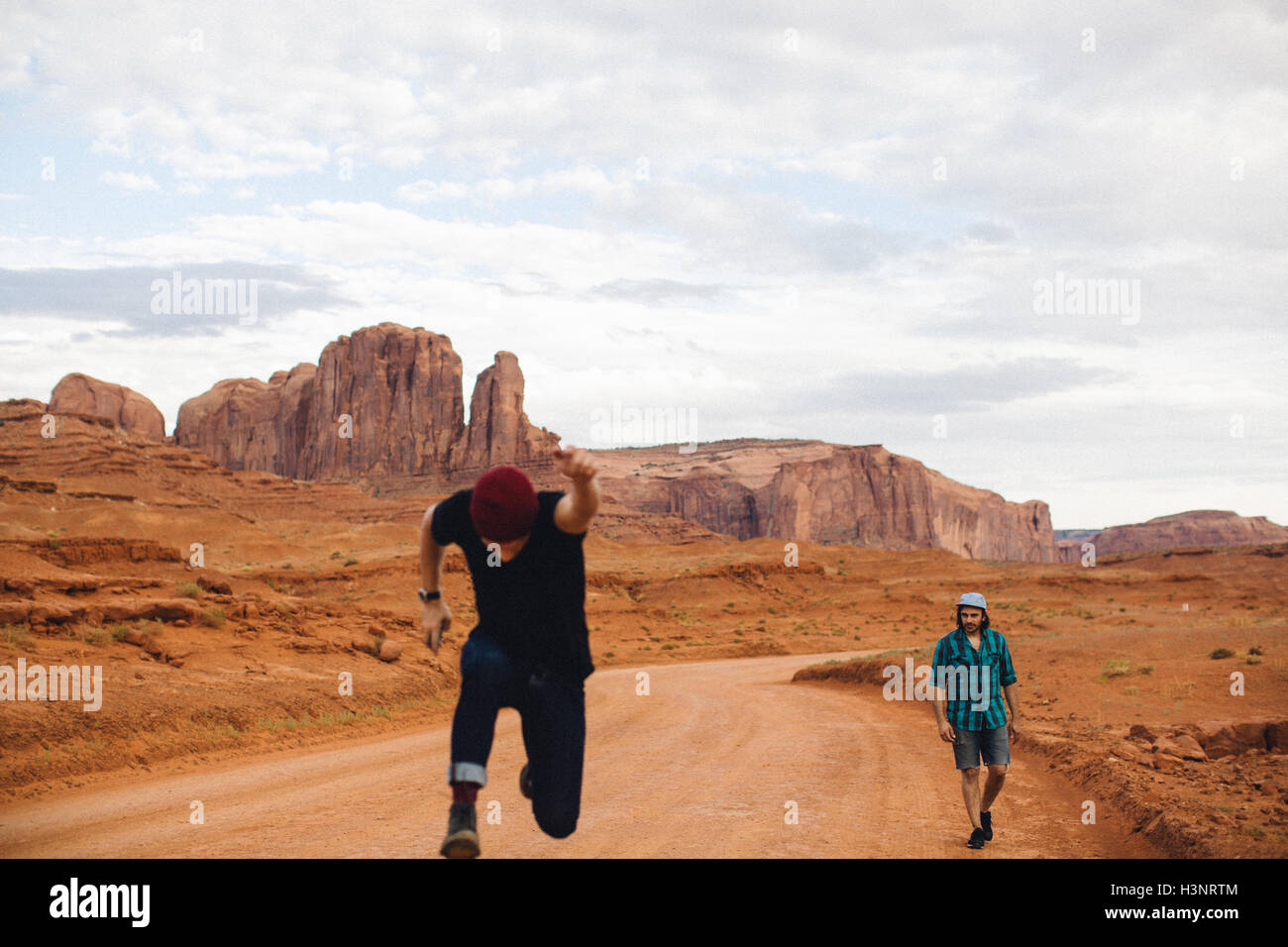 Zwei Männer, eine sprinten und eine zu Fuß über Feldweg, Monument Valley, Arizona, USA Stockfoto
