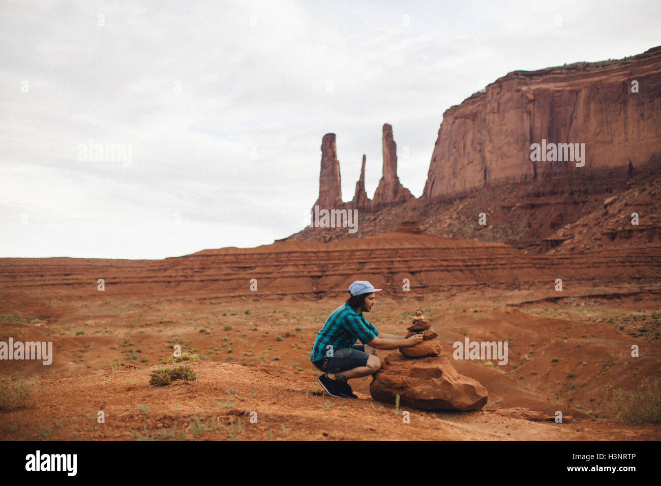 Junger Mann hocken, zu betrachten, gestapelte Felsen, Monument Valley, Arizona, USA Stockfoto