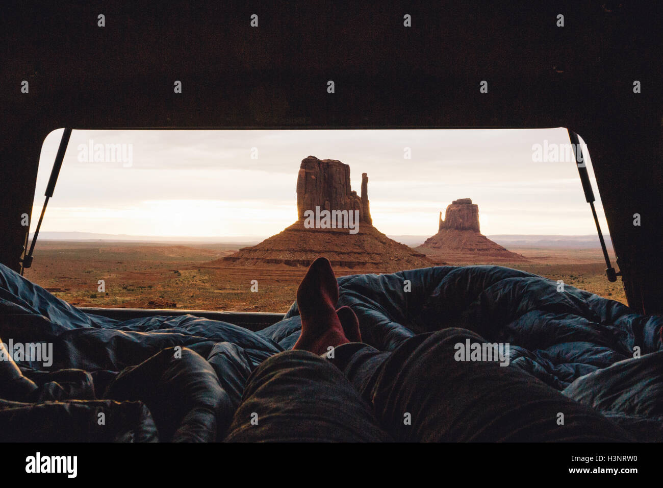 Männliche Beine und Füße entspannend innen Allradantrieb mit Blick auf Sandstein Buttes vom Kofferraum, Monument Valley, Arizona, USA Stockfoto