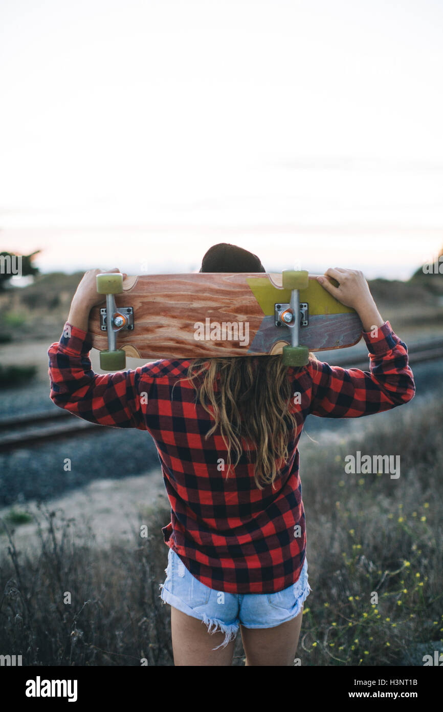 Frau mit Skateboard auf Schultern Stockfoto