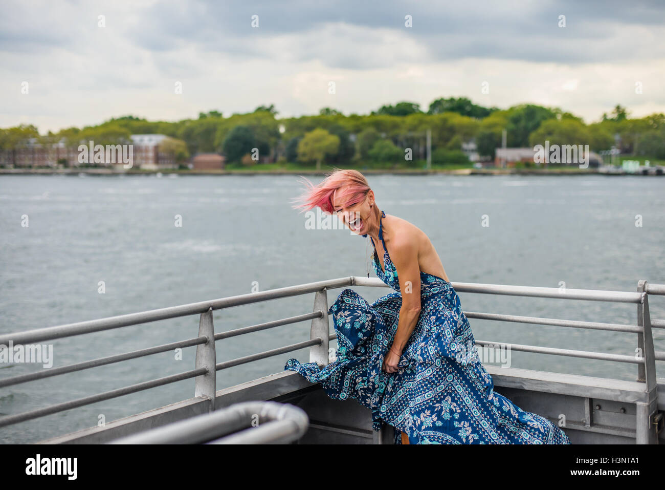 Reife Frau steht auf Boot, lachen, Wind weht Kleid Stockfoto