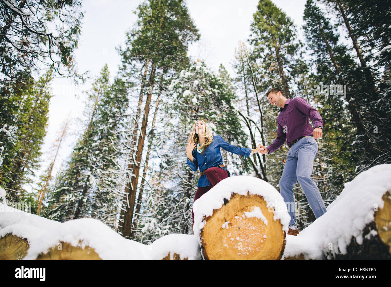 Paar im Waldklettergarten auf tief verschneiten Protokolle Stockfoto