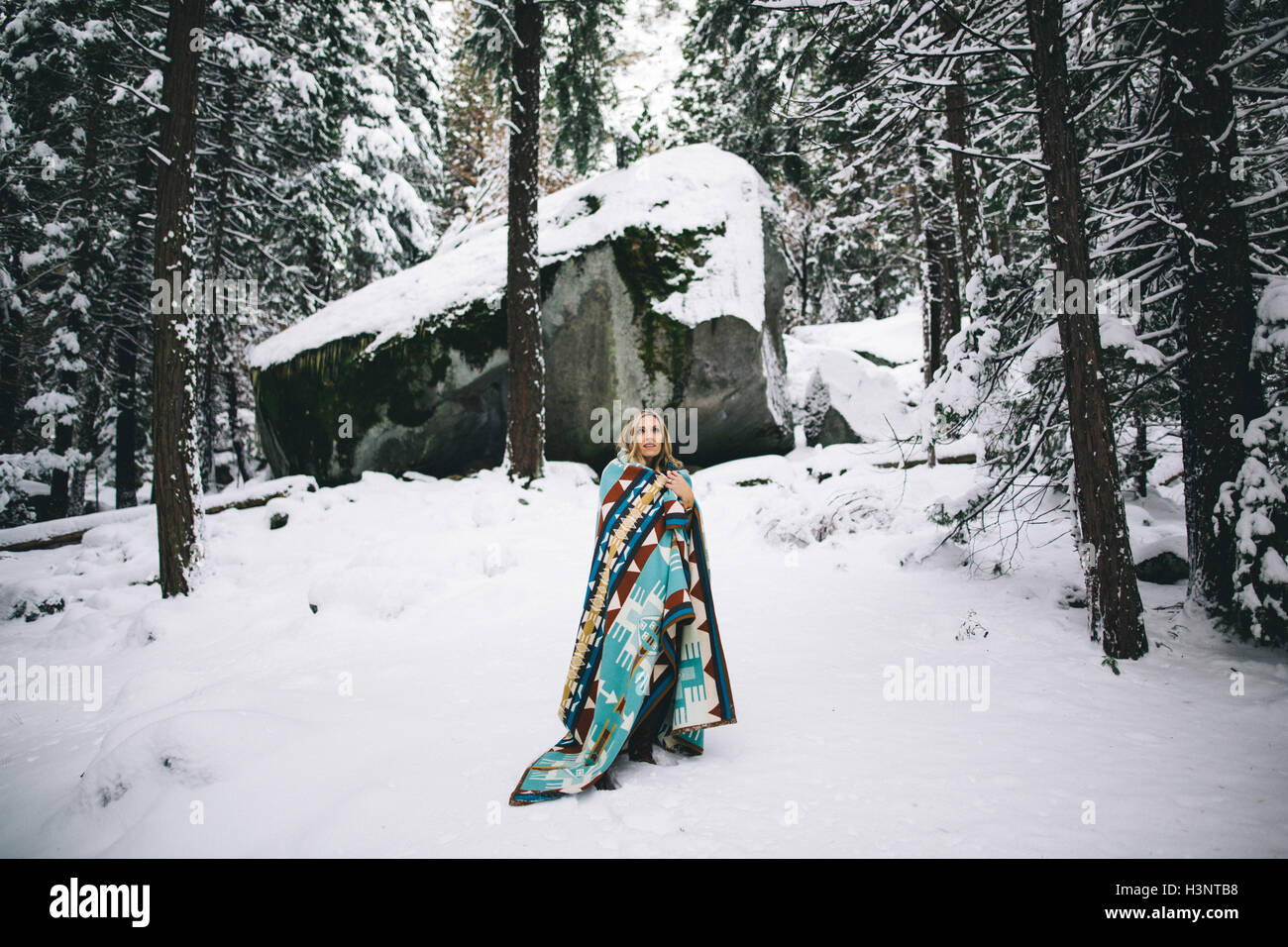 Frau im verschneiten Wald in Decke gehüllt Stockfoto