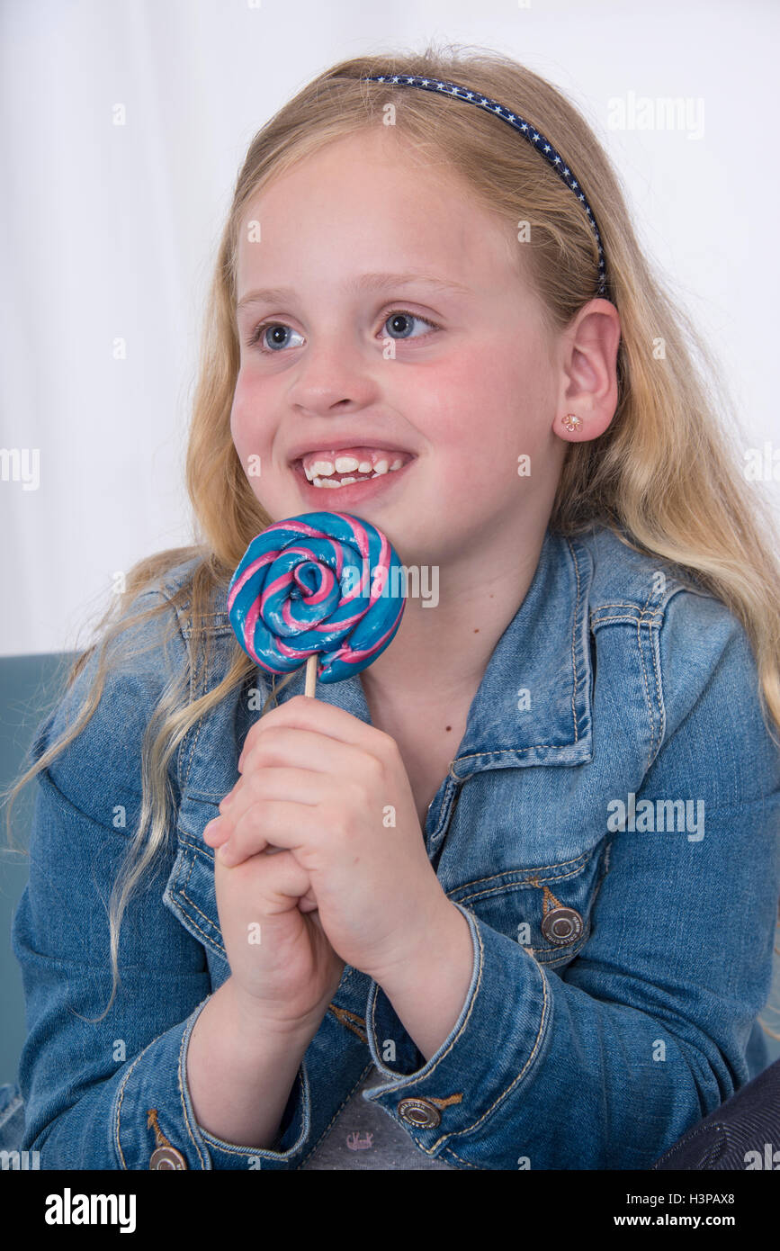 -MODELL VERÖFFENTLICHT. Mädchen hält Lolly pop, lächelnd. Stockfoto -MODELL VERÖFFENTLICHT. Mädchen hält Lolly pop, lächelnd. Stockfoto