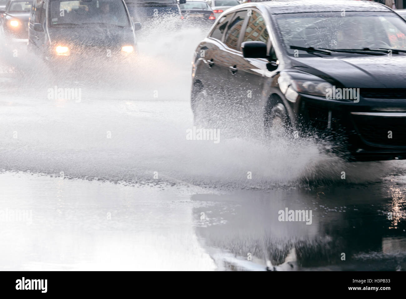 verschwommene Auto Flow während regnerischen Tag. Regen Wasser spritzt aus Autoreifen auf überschwemmten Straße. Stockfoto