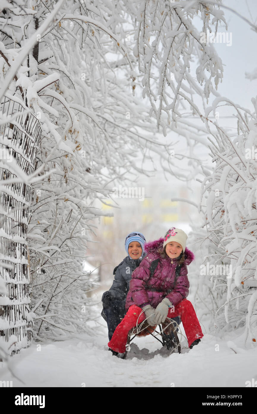 Glückliche Kinder schieben im Winterurlaub Stockfoto