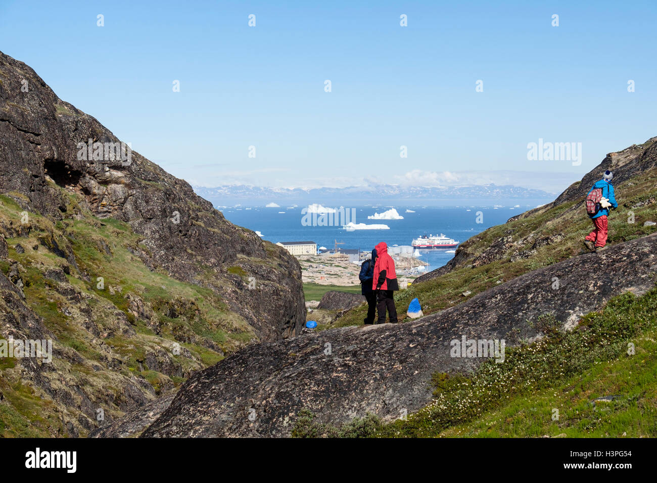 Blaue Route Trail mit Menschen wandern nach Ilulissat Iceford und Holms Bakke mit Stadt im Abstand unten im Sommer 2016. Ilulissat, Westgrönland Stockfoto
