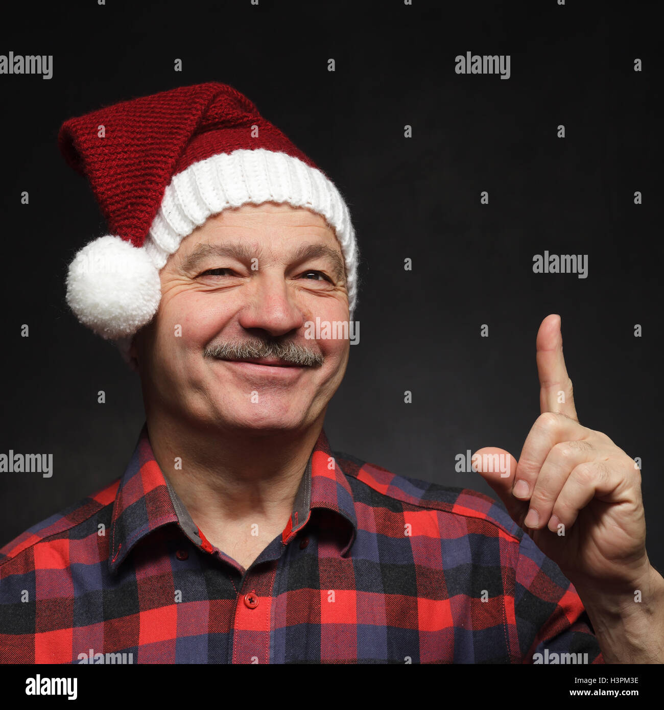 Mann mit einem Schnurrbart in GAP von Weihnachten zeigt Zeigefinger nach oben. Stockfoto