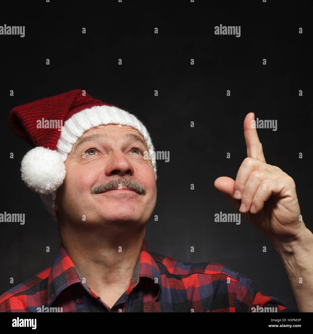 Mann mit einem Schnurrbart in GAP von Weihnachten zeigt Zeigefinger nach oben. Stockfoto