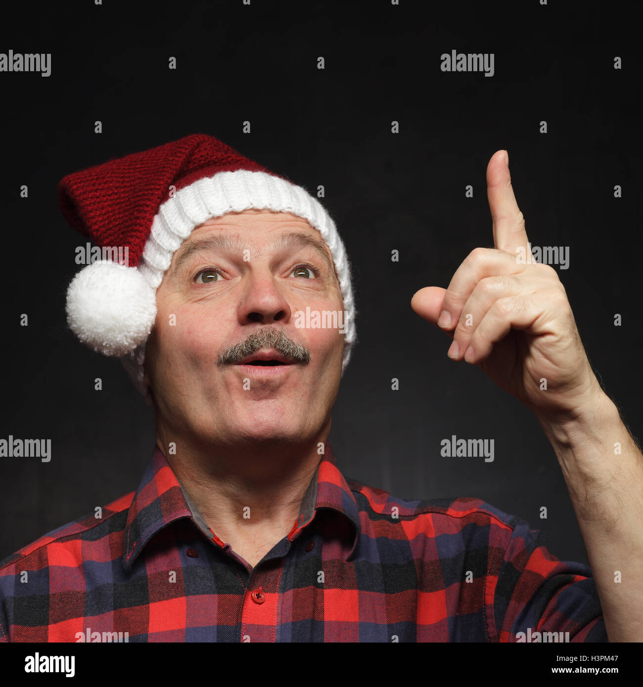 Mann mit einem Schnurrbart in GAP von Weihnachten zeigt Zeigefinger nach oben. Stockfoto