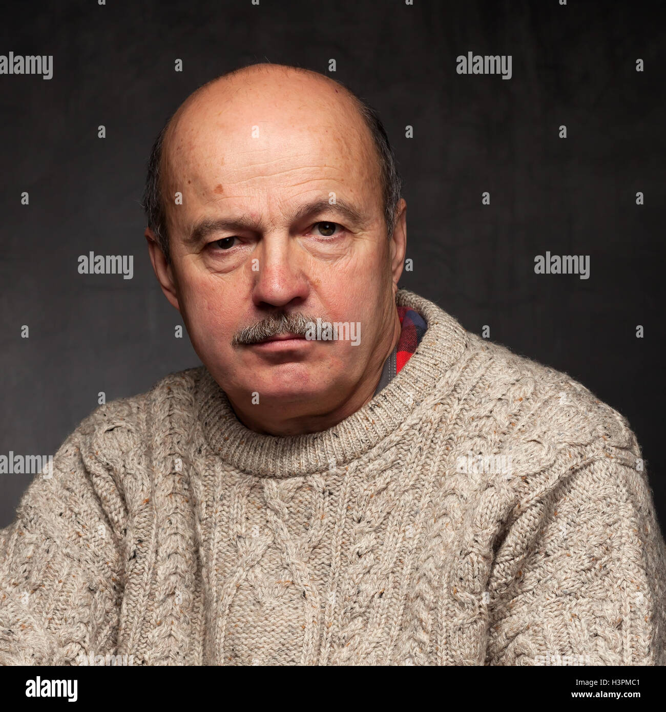 älterer Mann sitzt und schaut nachdenklich, Grübeln Problem oder komplexe Problem in Pullover. Stockfoto