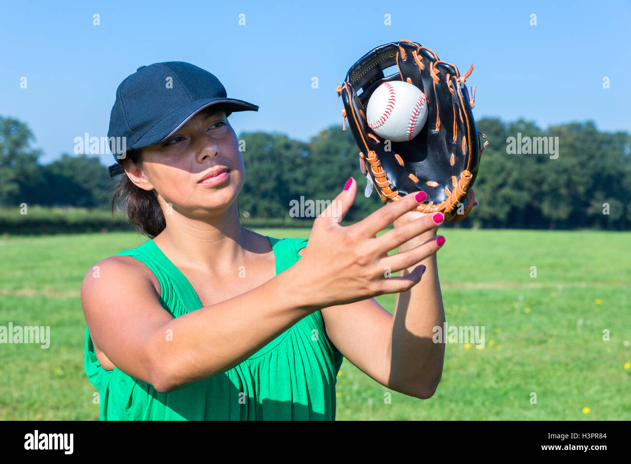 Frau mit Handschuh und Mütze fangen Baseball im freien Stockfoto