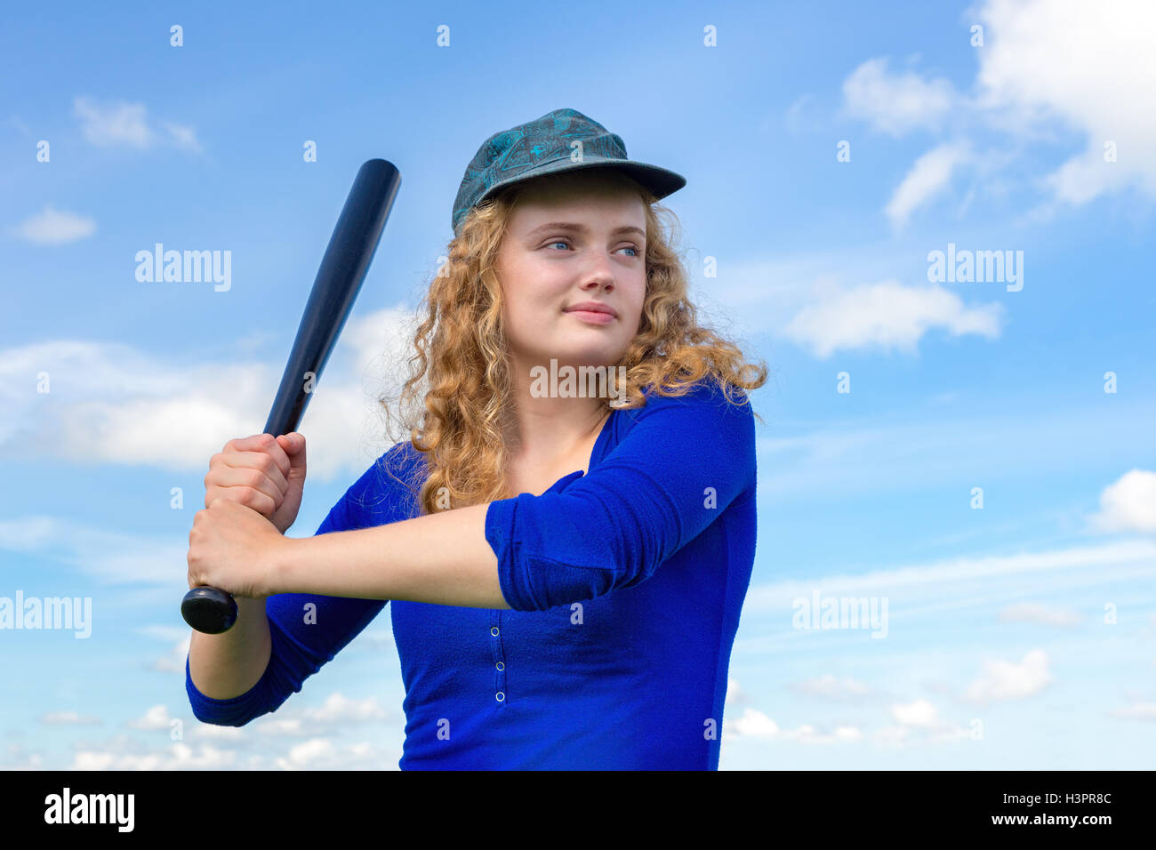 Junge Holländerin mit Baseballschläger und Kappe gegen blauen Himmel Stockfoto
