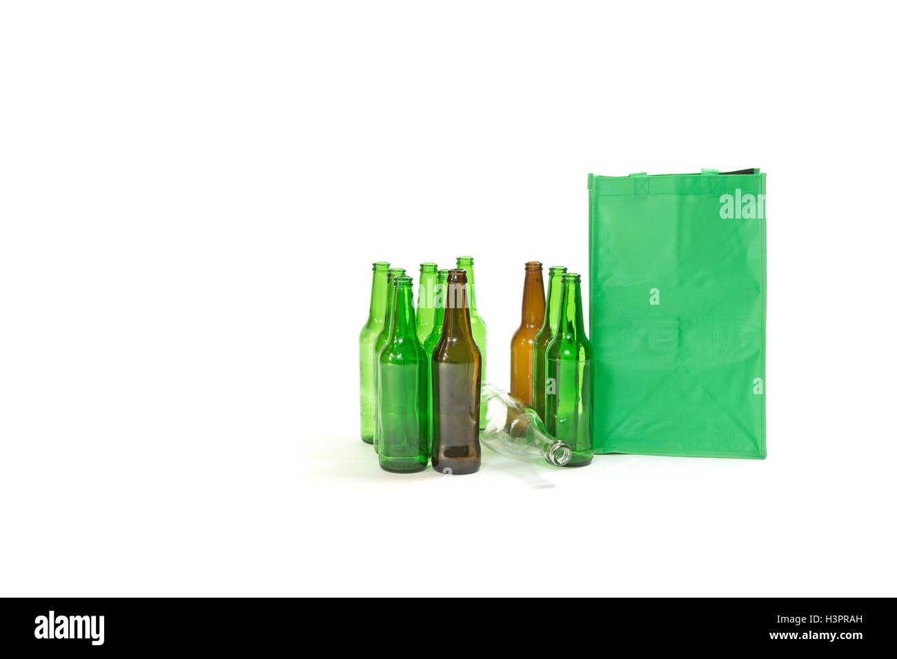 Gebrauchten Glasflaschen stehen auf dem weißen Hintergrund. Die leere grüne Tasche steht neben ihnen. Stockfoto