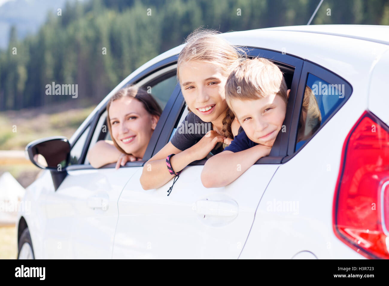 Glückliche junge Frau und ihren Kindern in einem Auto sitzen und blicken von Windows. Familienreisen-Hintergrundbild Stockfoto