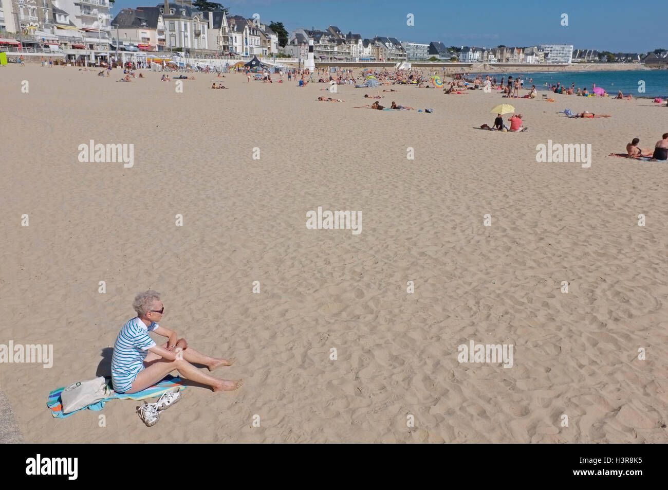 Eine pensionierte Frau sitzt allein an einem Strand in Frankreich Stockfoto