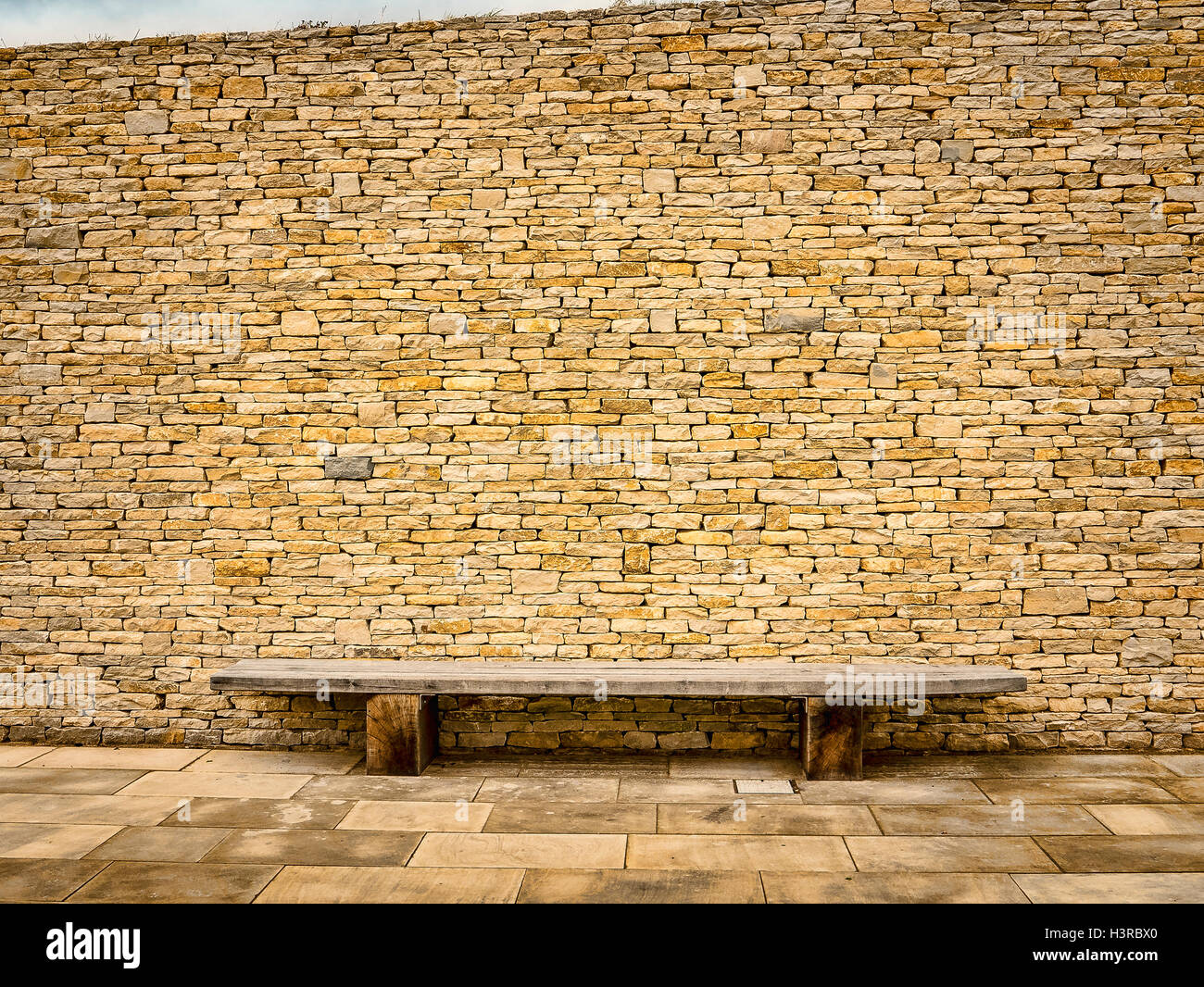 Eine Steinmauer mit hölzernen Sitzbank Stockfoto